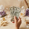 Hand holding money surrounded by crystals symbolizing abundance, wealth manifestation, and financial energy healing